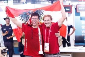 Zwei österreichische Tischler mit Flagge bei WorldSkills 2026.