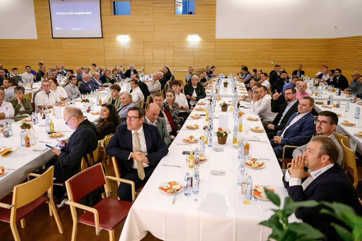 Landesinnungstagung 2026 – „Miteinander“ im Mittelpunkt Zahlreiche Teilnehmerinnen und Teilnehmer der Landesinnungstagung der NÖ Tischler 2026 sitzen an langen, festlich gedeckten Tischen in einem großen Veranstaltungssaal mit Holzwänden. Im Hintergrund ist eine Präsentationsfolie mit der Aufschrift „Rückblick 2026 / Ausblick 2027“ zu sehen.