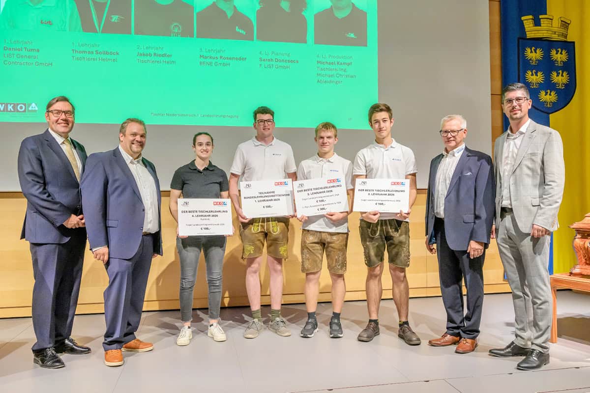 Landesinnungstagung 2026 – „Miteinander“ im Mittelpunkt Gruppenfoto bei der Landesinnungstagung der NÖ Tischler 2026: Vier ausgezeichnete Tischlerlehrlinge präsentieren ihre Urkunden und Preise, begleitet von vier Vertretern der Landesinnung. Im Hintergrund sind eine Präsentation zu den Lehrlingsauszeichnungen sowie das niederösterreichische Landeswappen zu sehen.